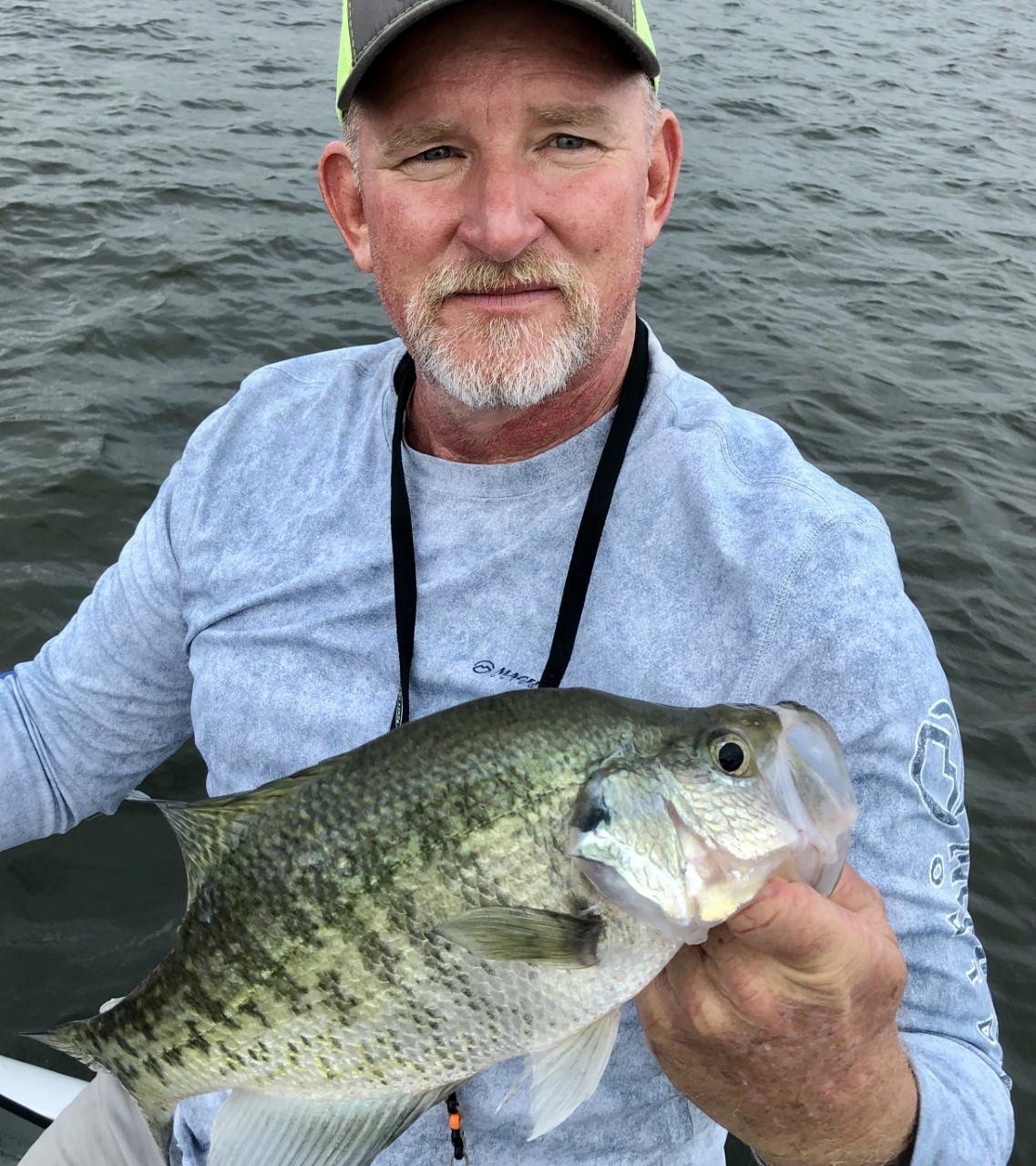 A man holding a fish while sitting on top of a boat.